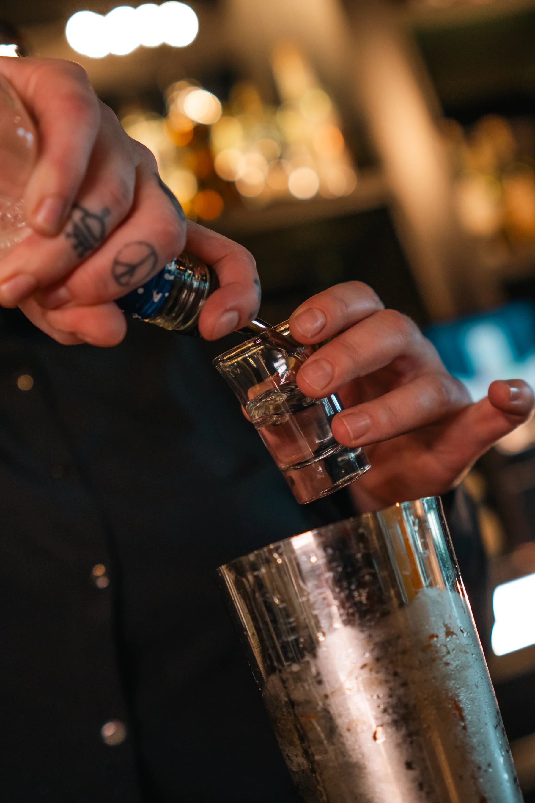 A bartender measures a spirit for a cocktail